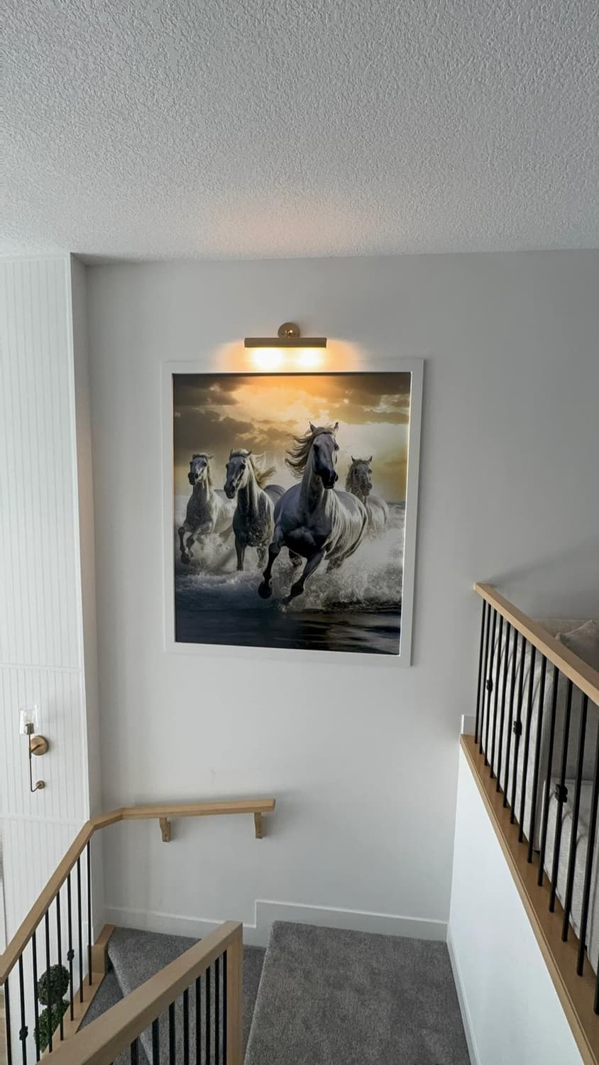 Framed print of galloping horses installed on a stairwell wall