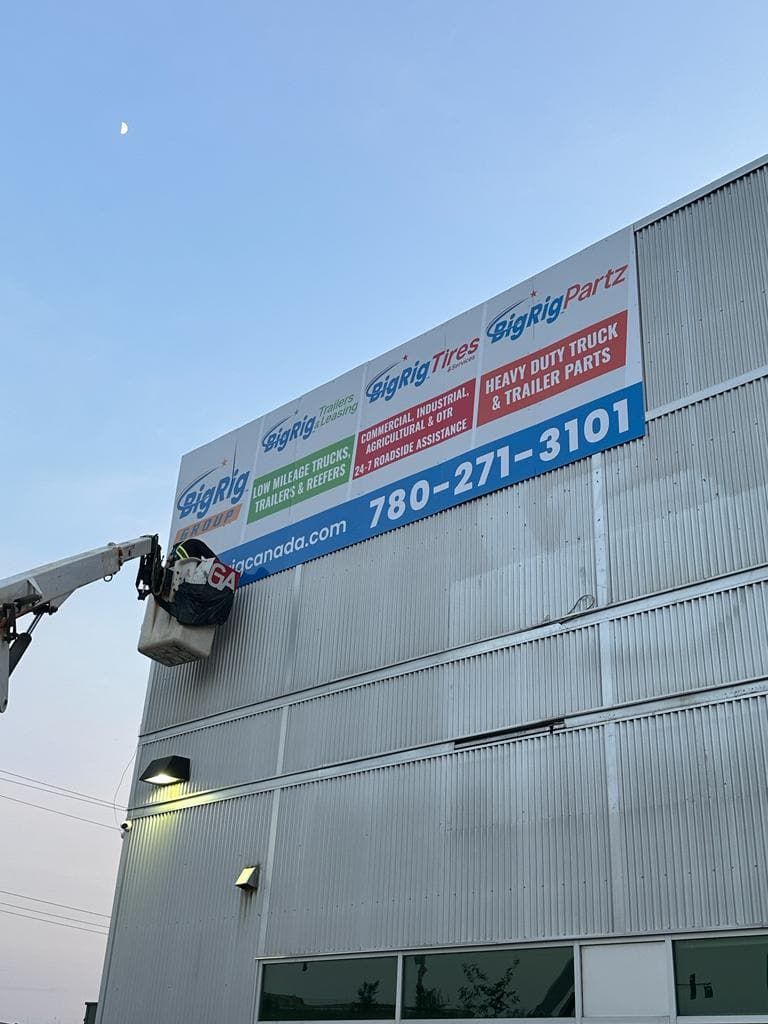 Installing BigRig Group sign on a bucket lift